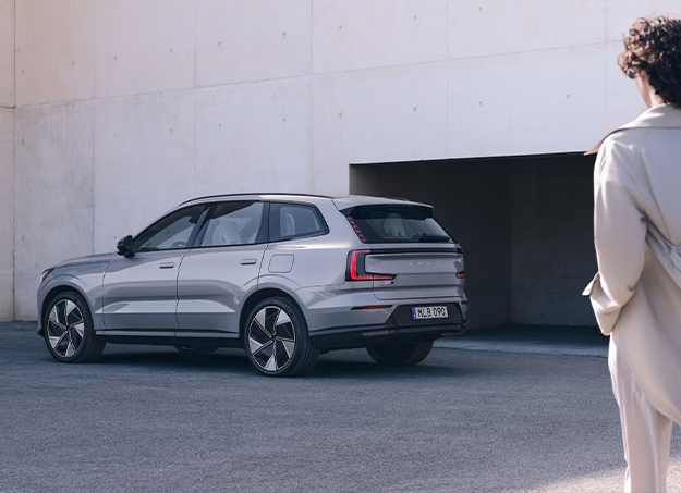 Volvo EX90 électrique stationné devant un paysage urbain moderne